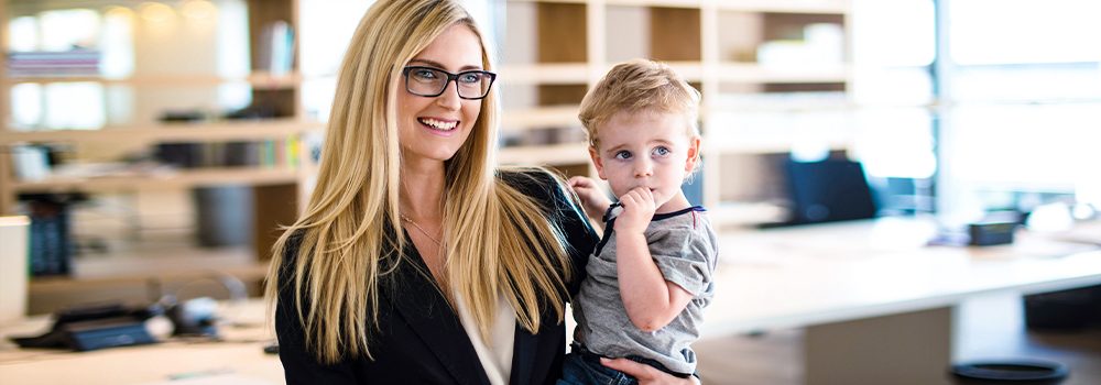 Zurück in den Job: Mutter und Karrierefrau stellt ihren kleinen Sohn nach der Elternzeit auf der Arbeit vor