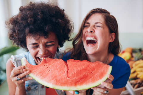 Die smarte Budgetierung: Zwei junge Frauen teilen sich ein Stück Wassermelone und haben viel Spaß dabei