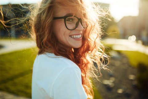 volksbank mittelhessen zukunftsplanerin Portrait einer jungen Frau mit zauberhaften lächeln und roten Haaren steht im Wind im Stadtzentrum