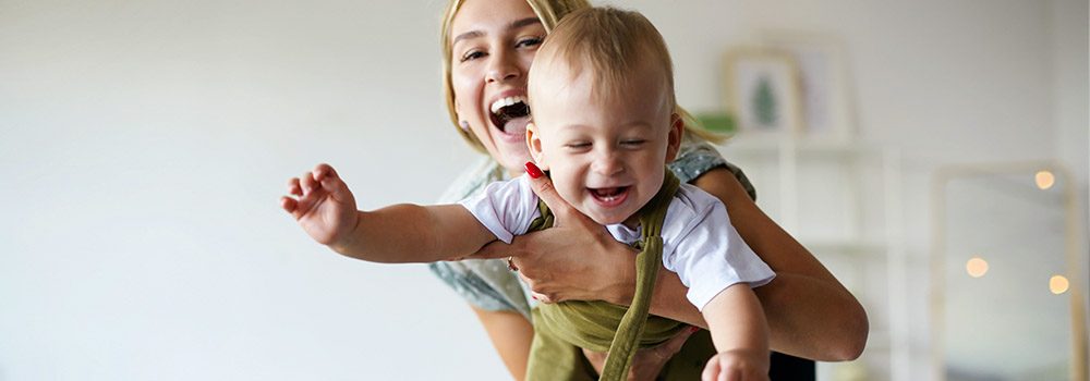 volksbank mittelhessen zukunftsplanerin glückliche junge Mutter, die ihren süßen kleinen Sohn wie ein fliegendes Flugzeug hält